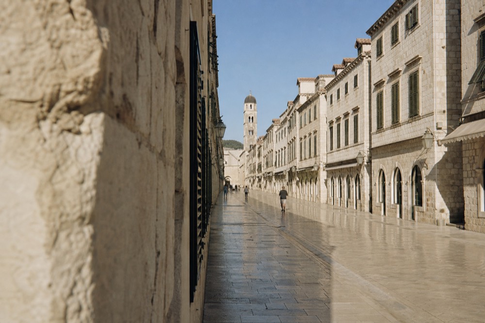 A view of the Old Town's main street, the Stradun, with limestone buildings on both sides and the bell tower in the distance