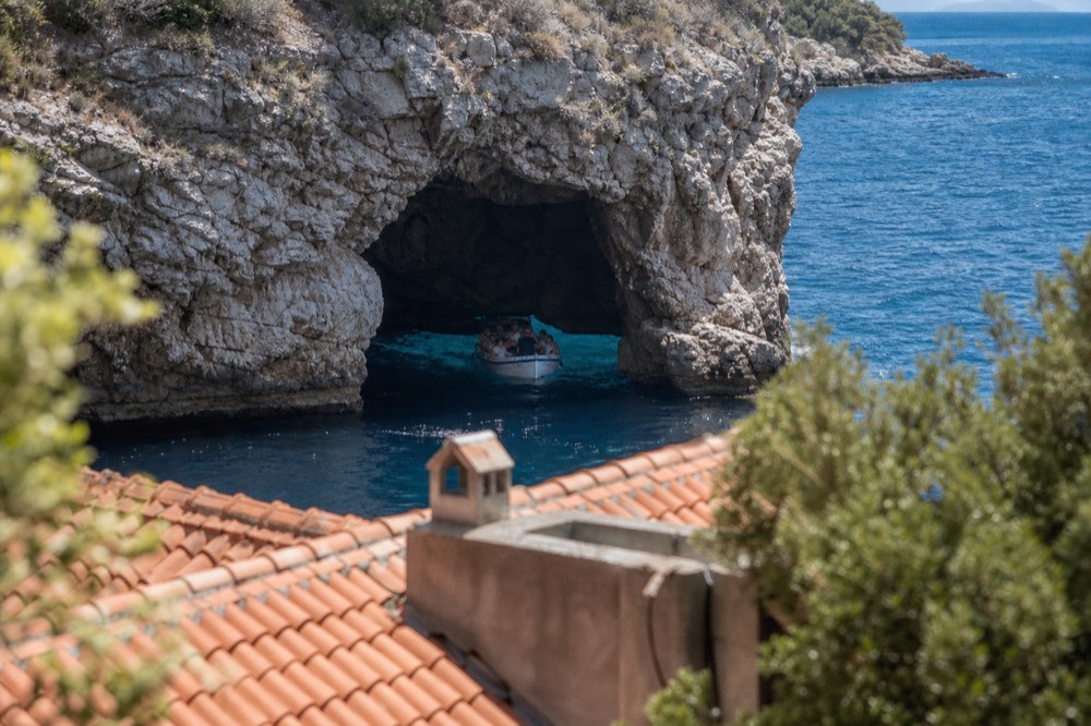 A boat entering a sea cave with bright turquoise water glowing inside