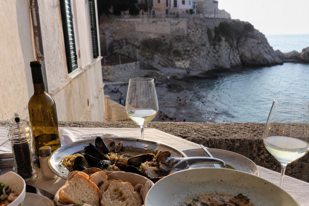 Autumn terrace lunch with wine glasses, bread and a platter of shellfish in late afternoon sun