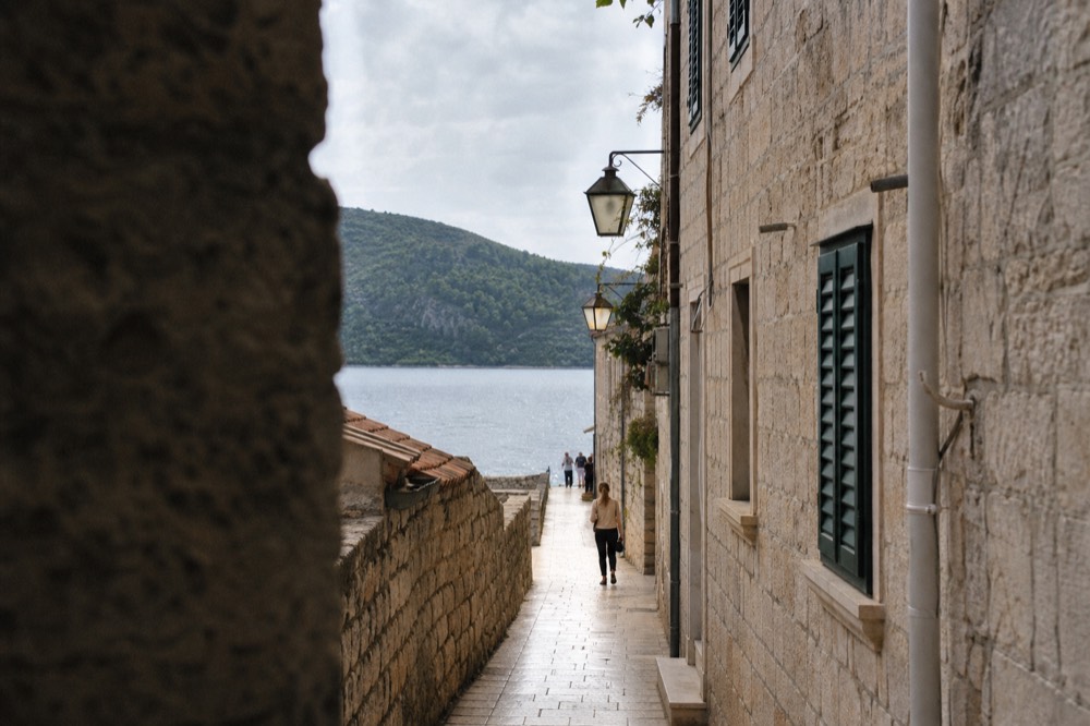 Stone alley in Korčula old town with sunlight on polished paving and green shutters