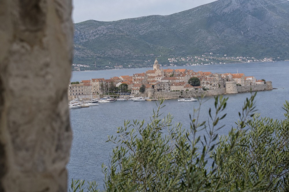 A stone walled old town on a peninsula with terracotta roofs and boats in the harbour