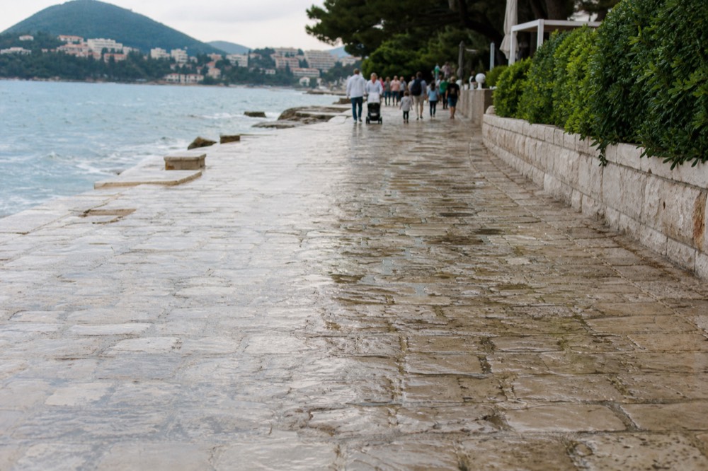 Lapad Beach promenade with cafes and families walking along the shore