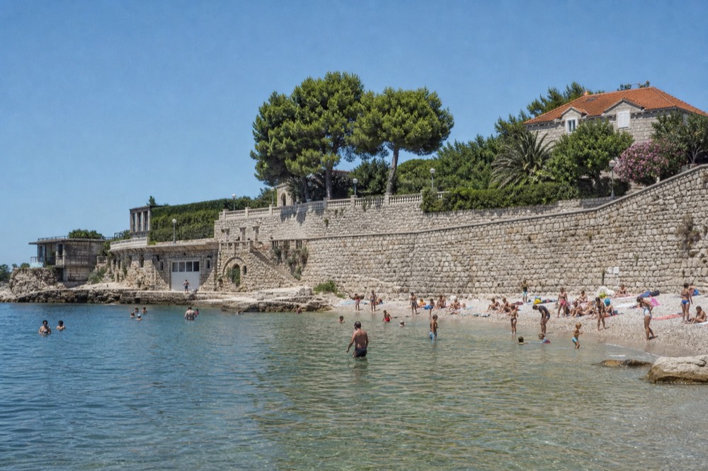 Lapad Beach with local families and children playing in the shallow water