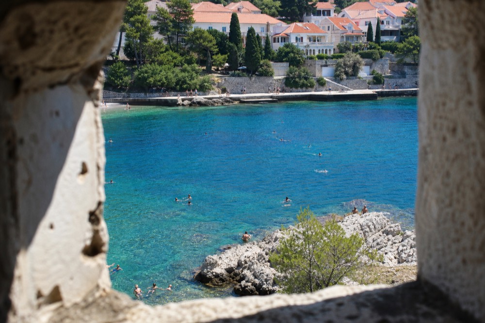 Swimmers in the clear water at Lapad Beach with the promenade in the background