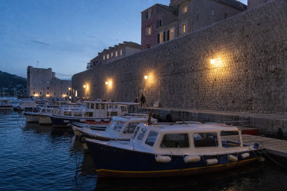 Row of small passenger boats bobbing at wooden pontoons in Dubrovnik Old City Harbour