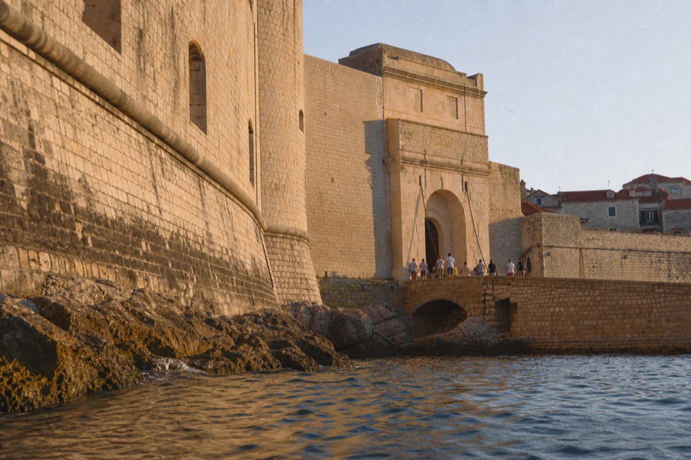 Stone gateway leading into Dubrovnik Old Town with people walking through