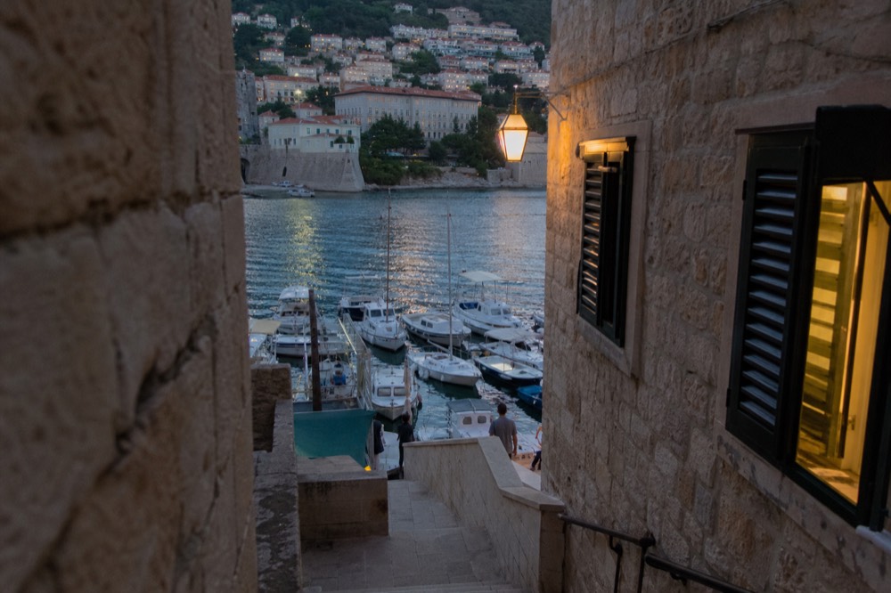 Harbour water with boats moored against a stone quay in late afternoon light