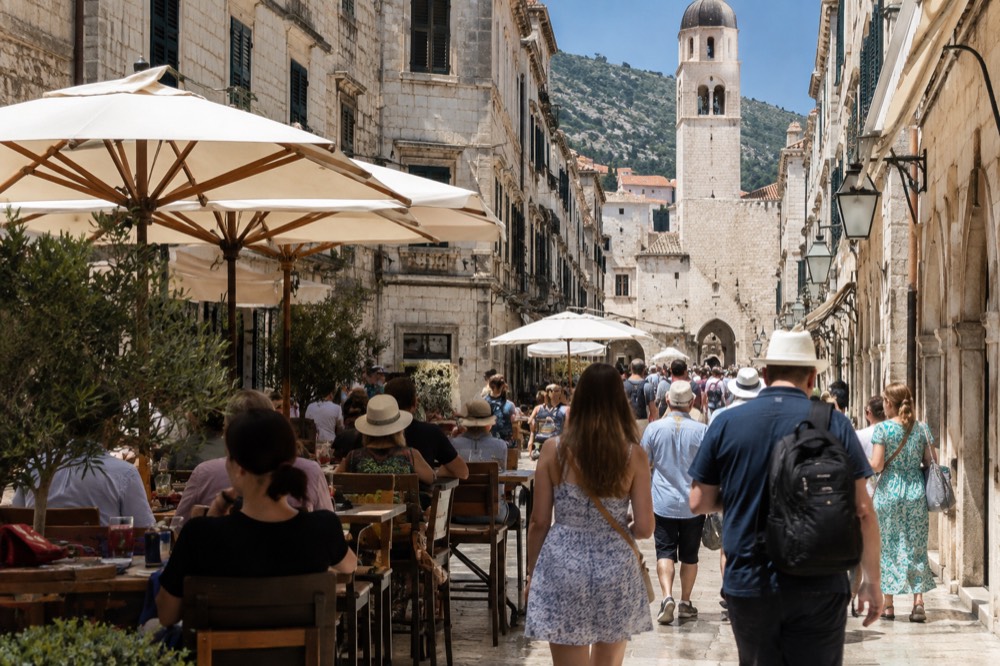 Crowded limestone street with cafe tables in Dubrovnik at midday