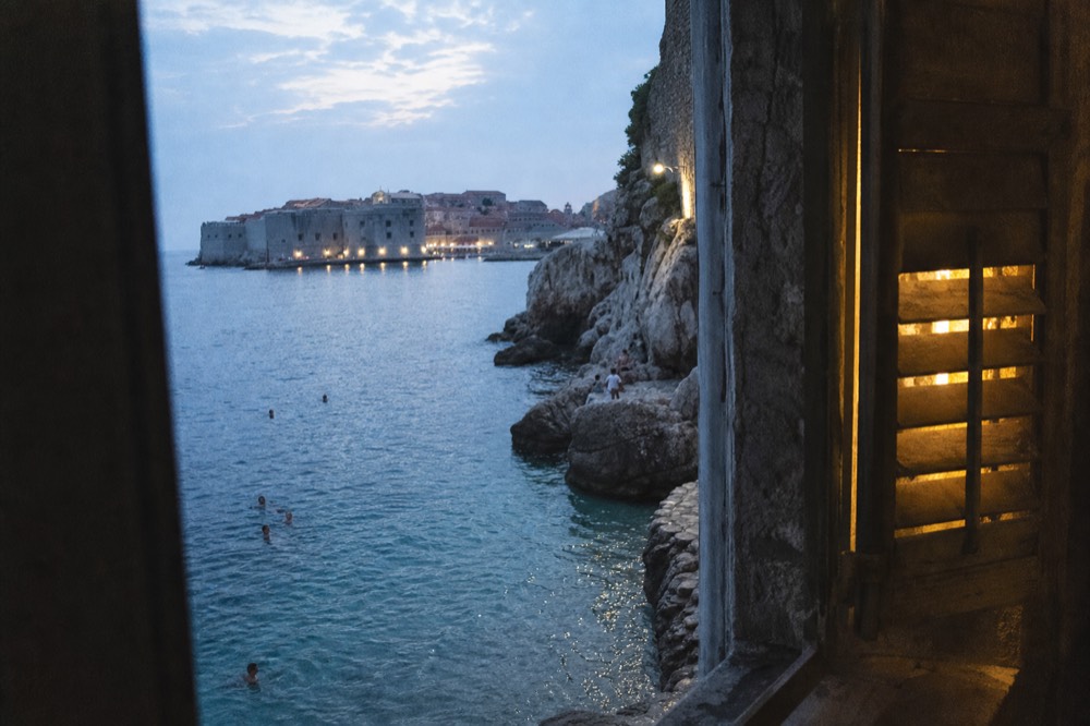 Swimmers in clear blue water beside rocky shoreline near Dubrovnik