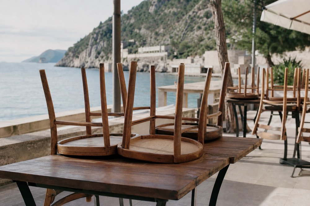 Sunlit empty restaurant terrace in the morning before service with chairs upturned on tables