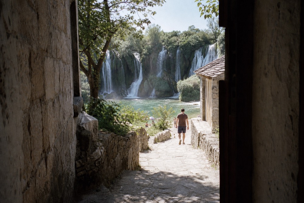 Kravica waterfalls spreading in a wide white curtain across a green rock face