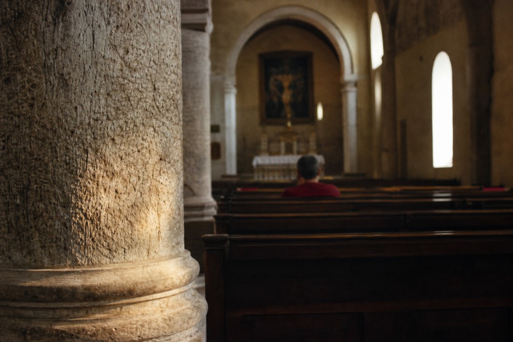 A quiet stone church interior with rows of wooden pews and soft light