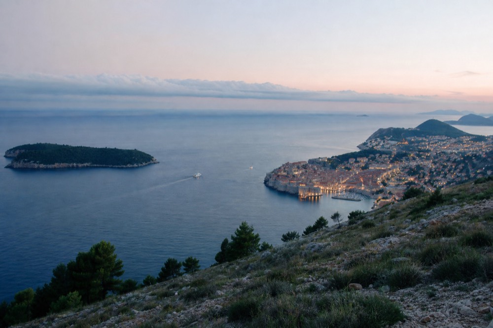 Evening lights beginning to glow in Dubrovnik Old Town as dusk settles over the coast seen from Mount Srd
