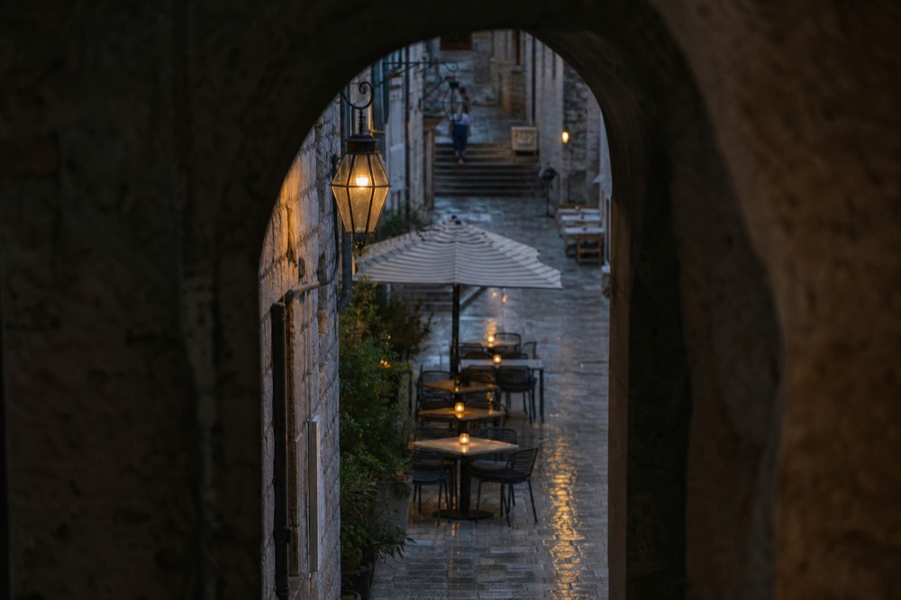 Outdoor cafe tables with candles on a narrow stone street in Dubrovnik at night