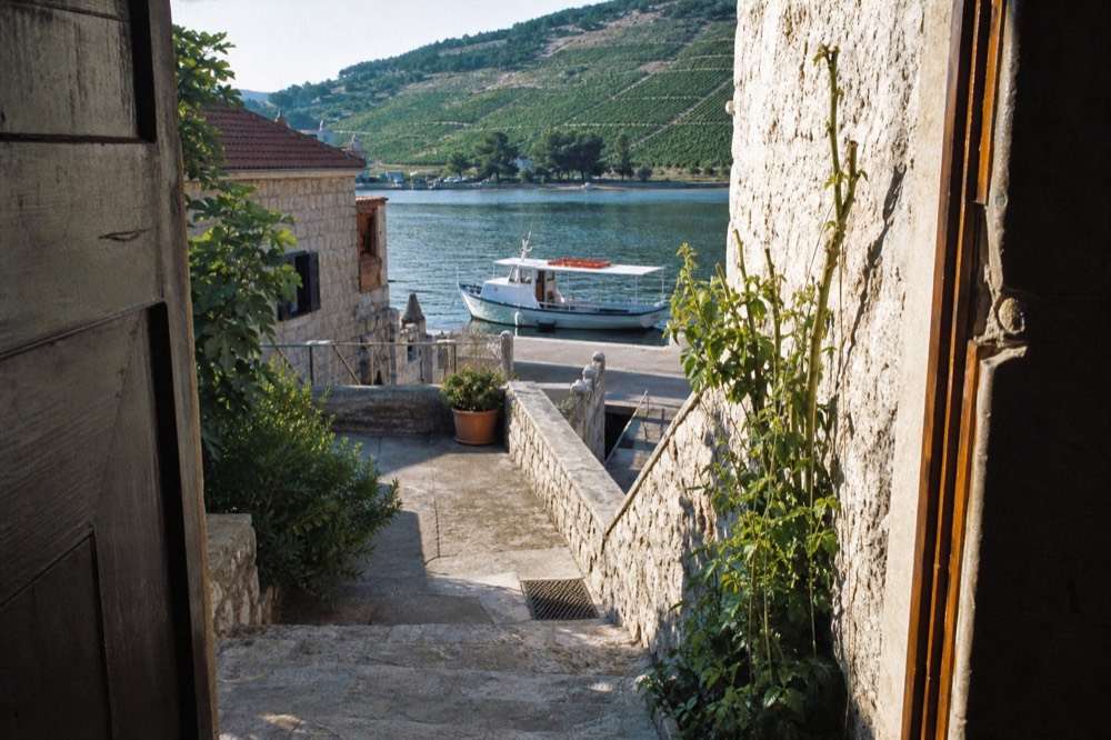 A boat moored in a small harbour with vineyard hills behind it