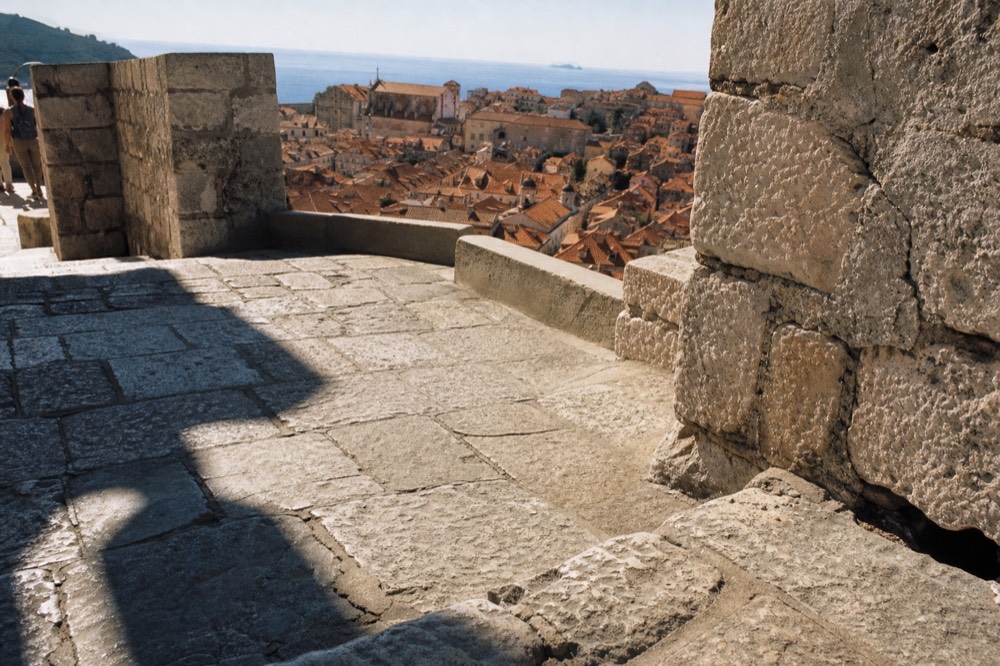 Terracotta rooftops of a walled Adriatic town seen from a high stone tower