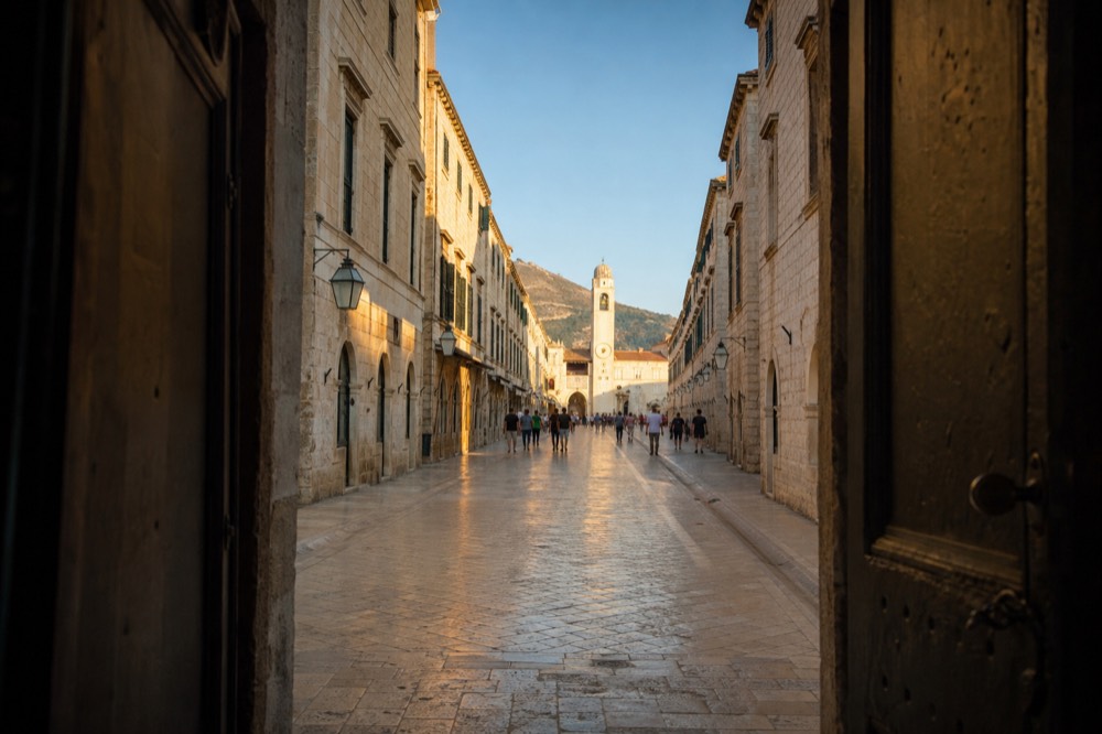 Long limestone street lined by uniform stone facades leading to a clock tower
