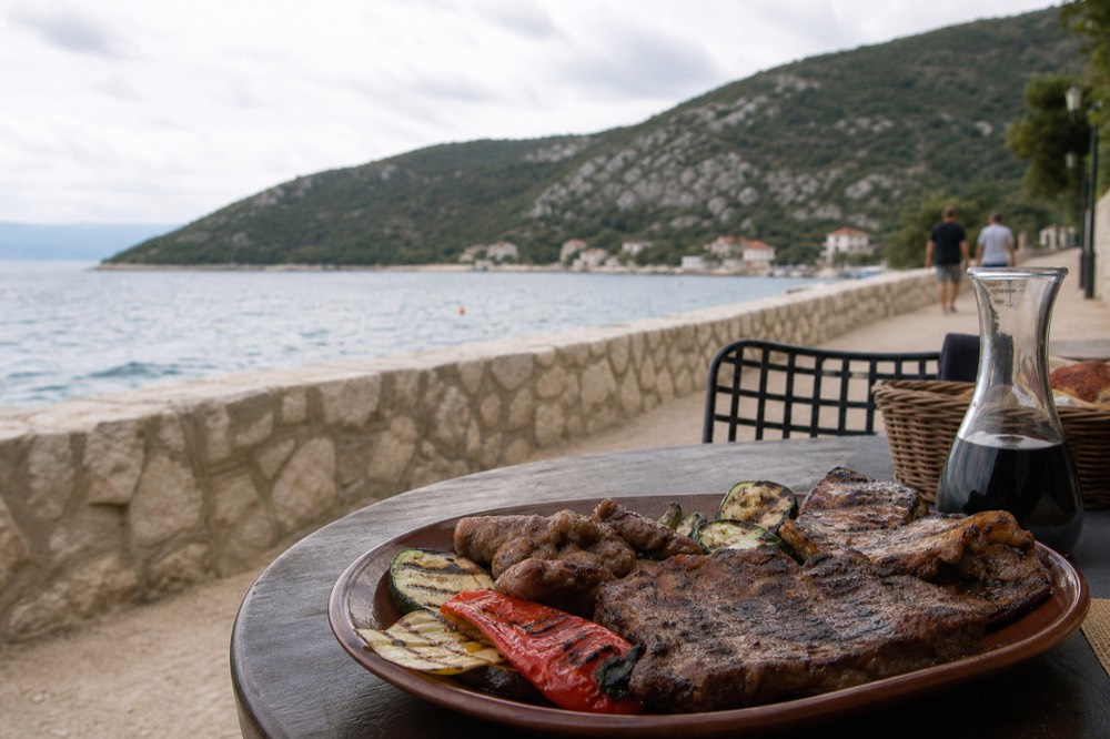 Grilled meat and vegetables served on a rustic plate at an outdoor table