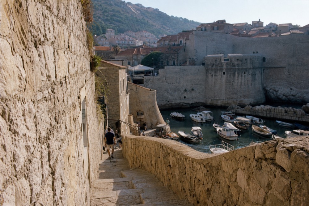 Small stone harbour with wooden boats moored below the city walls