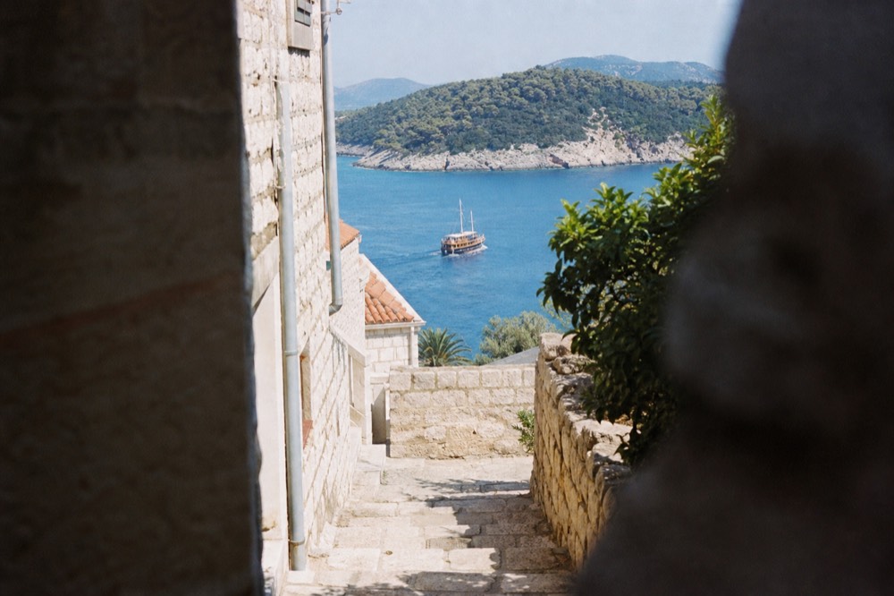 A wooden boat cruising past green islands on the Adriatic sea near Dubrovnik