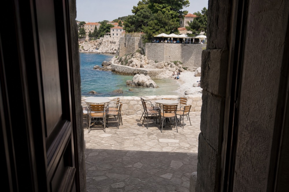 A cafe terrace on a stone square in Dubrovnik with menus displayed outside