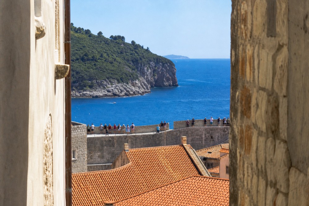 Walkers on the city walls of Dubrovnik above red rooftops and the Adriatic Sea