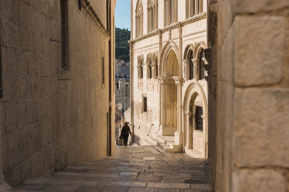 Ornate carved portal and arched windows of a stone palace facade lit by afternoon sun