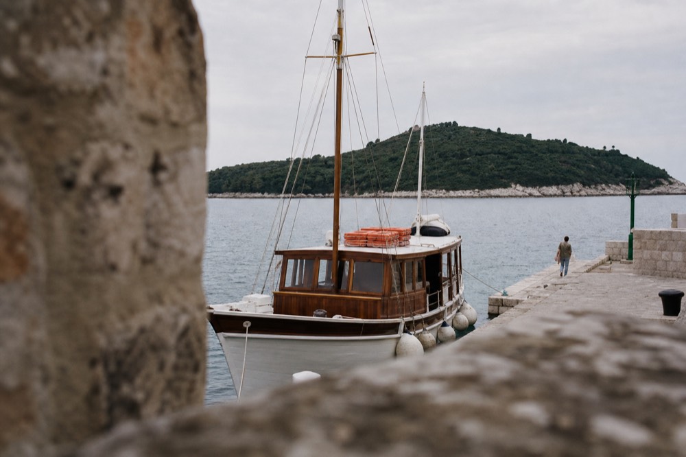 Wooden passenger boat moored at a stone quay with a green island across the water