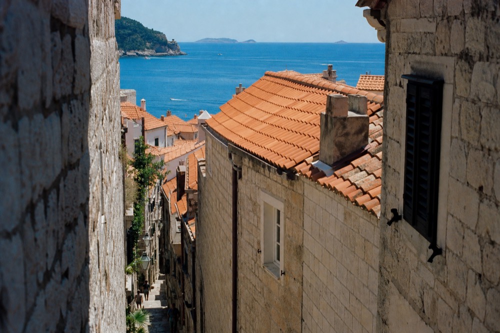 A narrow stone lane in the Old Town with fresh orange roof tiles visible above the facades