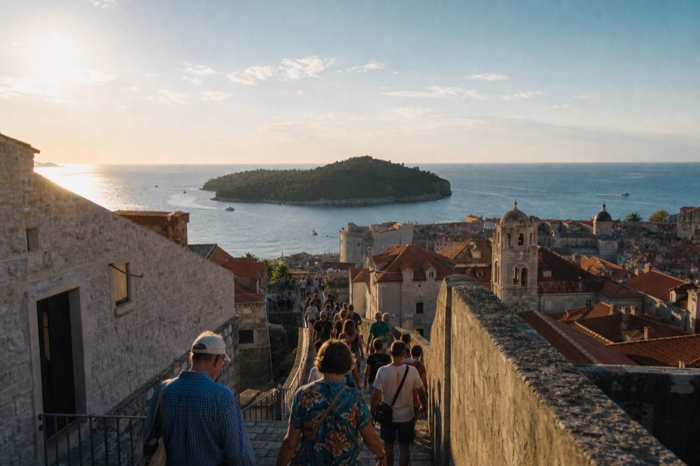 A crowded stone street in the Old Town seen from above with tour groups walking