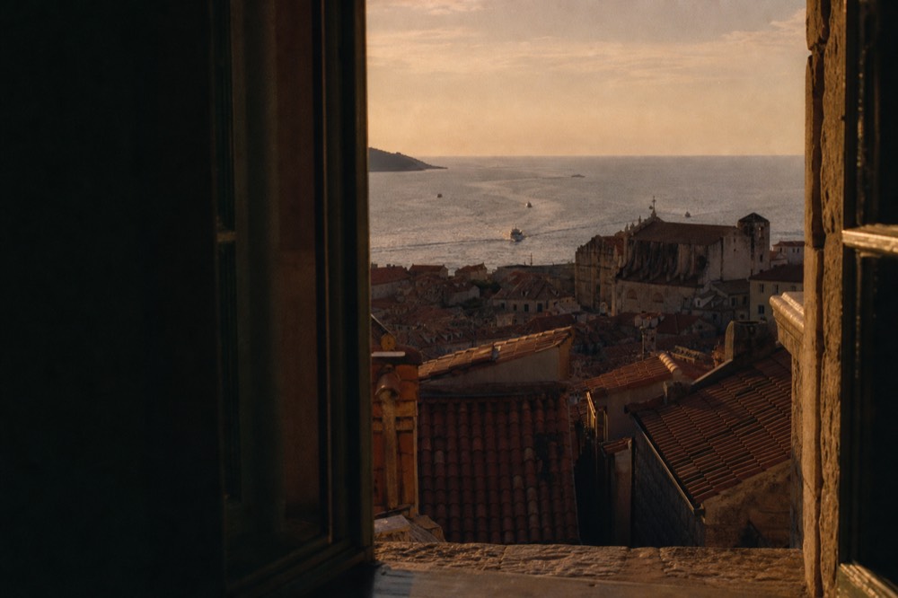 The Old Town of Dubrovnik at dusk with warm light on the rooftops and the sea beyond