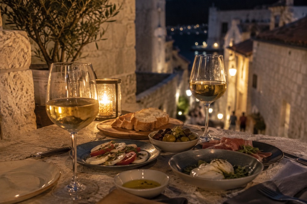 Wine glasses and a small plates dinner on a stone terrace at night