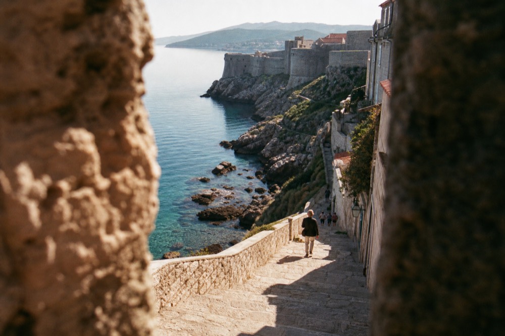 The stone city walls of Dubrovnik rising above calm turquoise sea