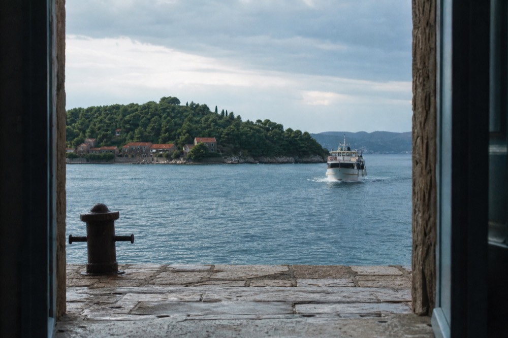 A passenger boat approaching a green island with a small stone village