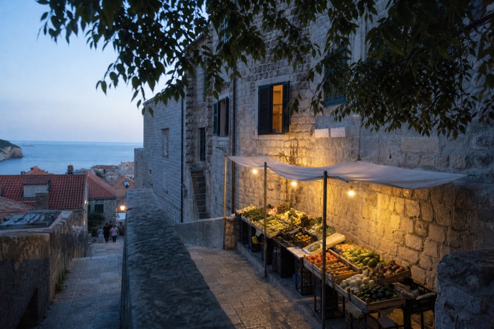 A market stall with fresh produce beside a stone building in Dubrovnik