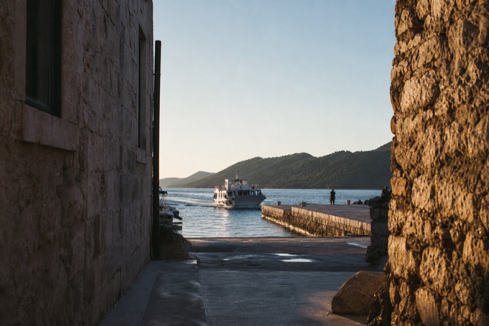A small passenger ferry approaching a stone quay on an island harbour
