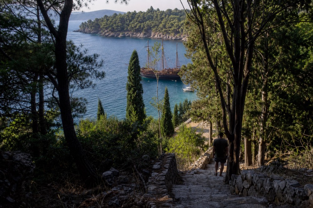 A wooden sailing ship with masts and rigging anchored in a bay