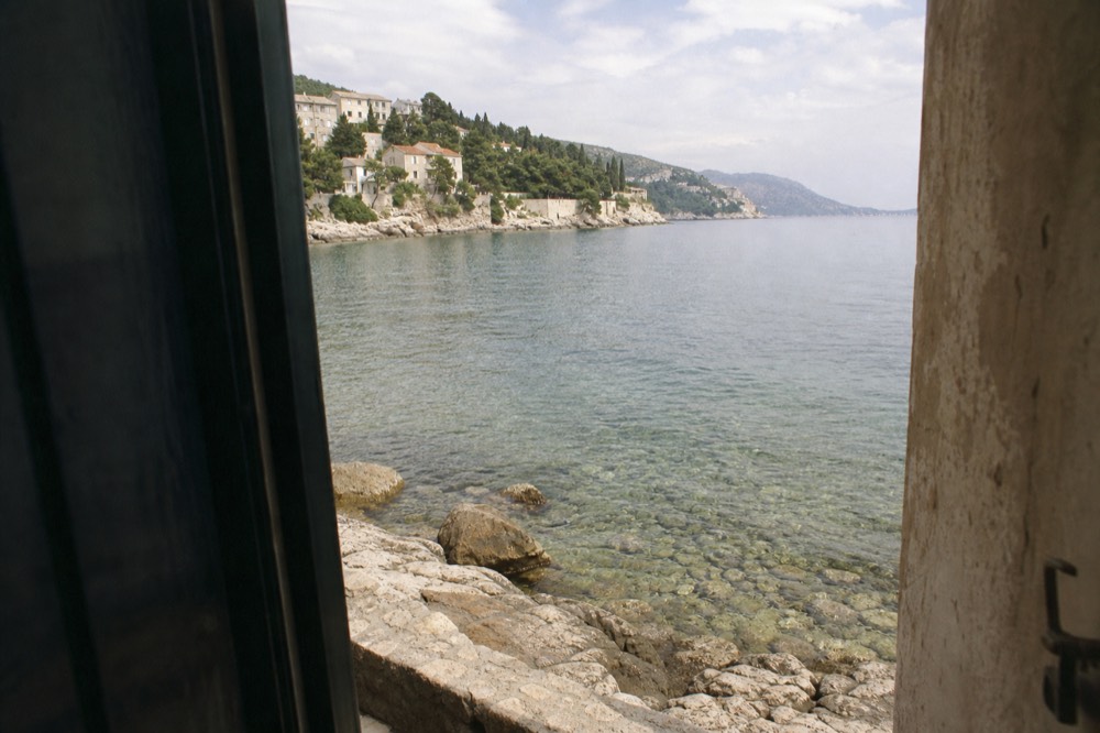 Rocky shoreline with clear shallow water and underwater stones visible near Dubrovnik