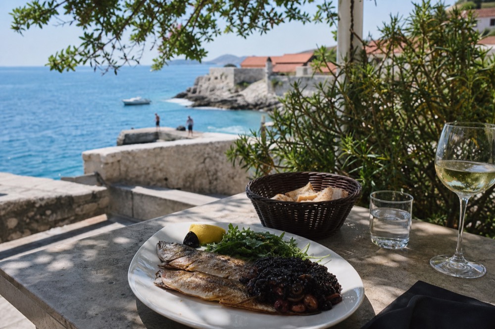 A plate of grilled fish and black risotto on a stone tavern table