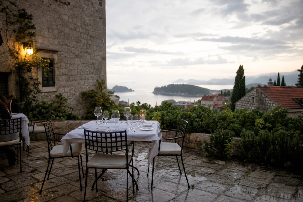 An elegantly set restaurant table with white linen and wine glasses at dusk