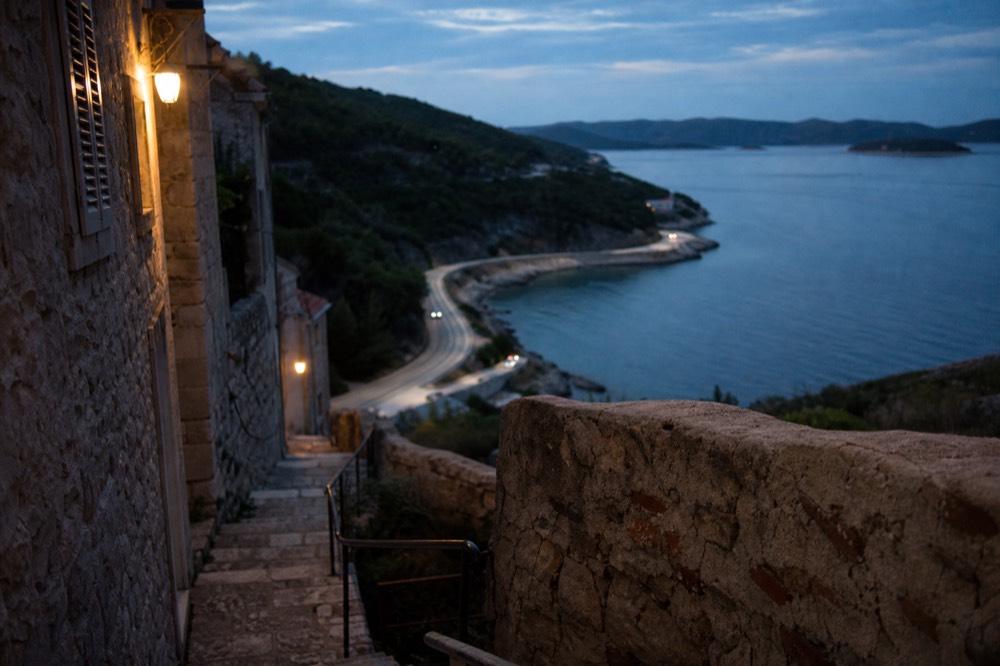 A coastal road curving along a peninsula with calm blue water below