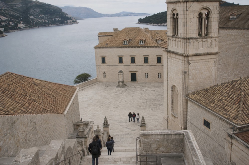 Flat paved square in Dubrovnik Old Town beside a stone bell tower