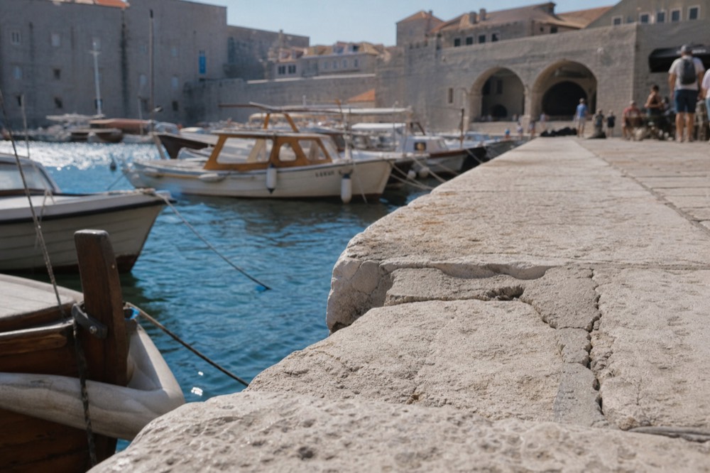 Harbour quay in Dubrovnik with moored wooden boats and flat stone paving
