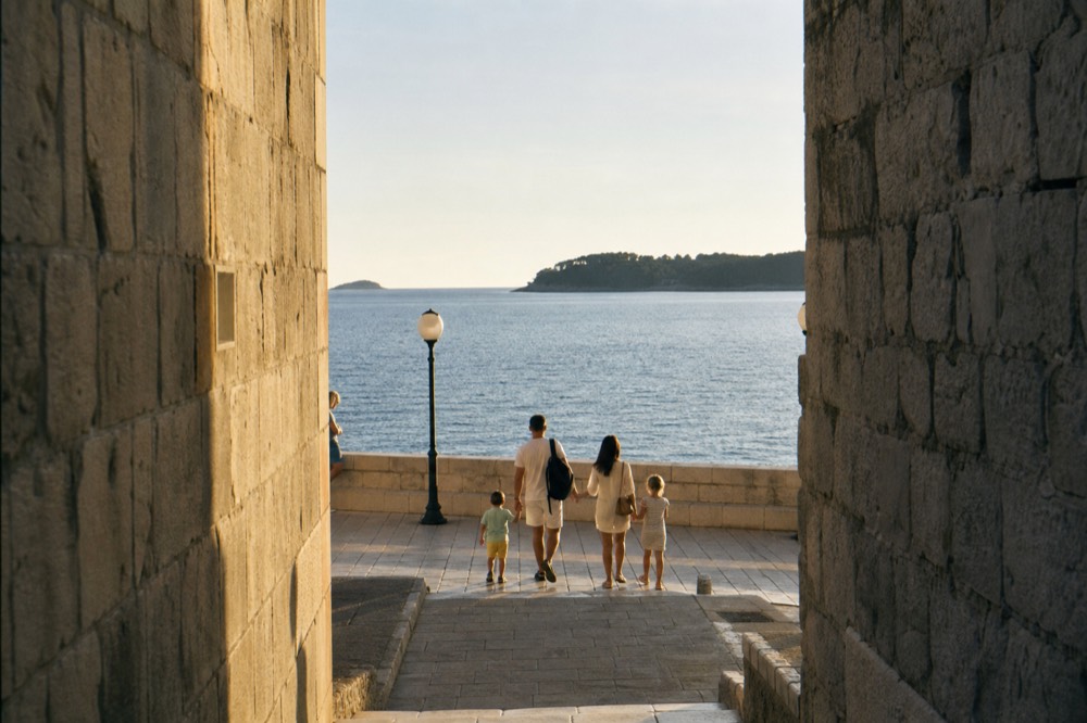 Family strolling a wide flat seaside promenade in late afternoon light