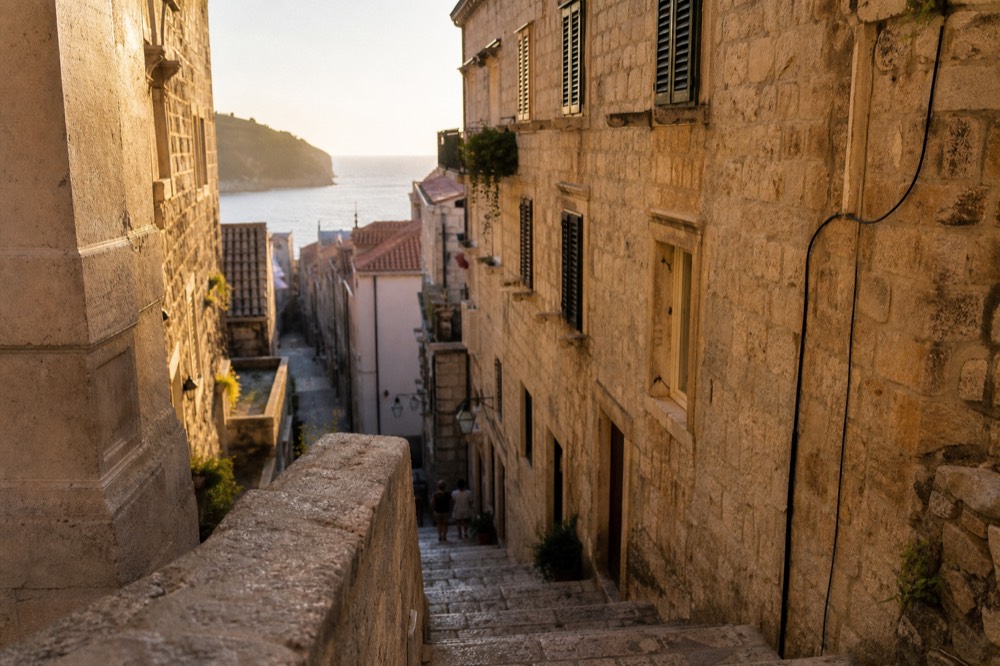 A narrow stone lane in Dubrovnik Old Town with worn limestone steps and shuttered windows