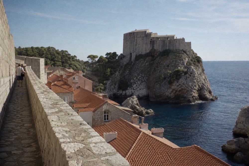 A stone fortress on a rocky outcrop above the sea under a wide evening sky