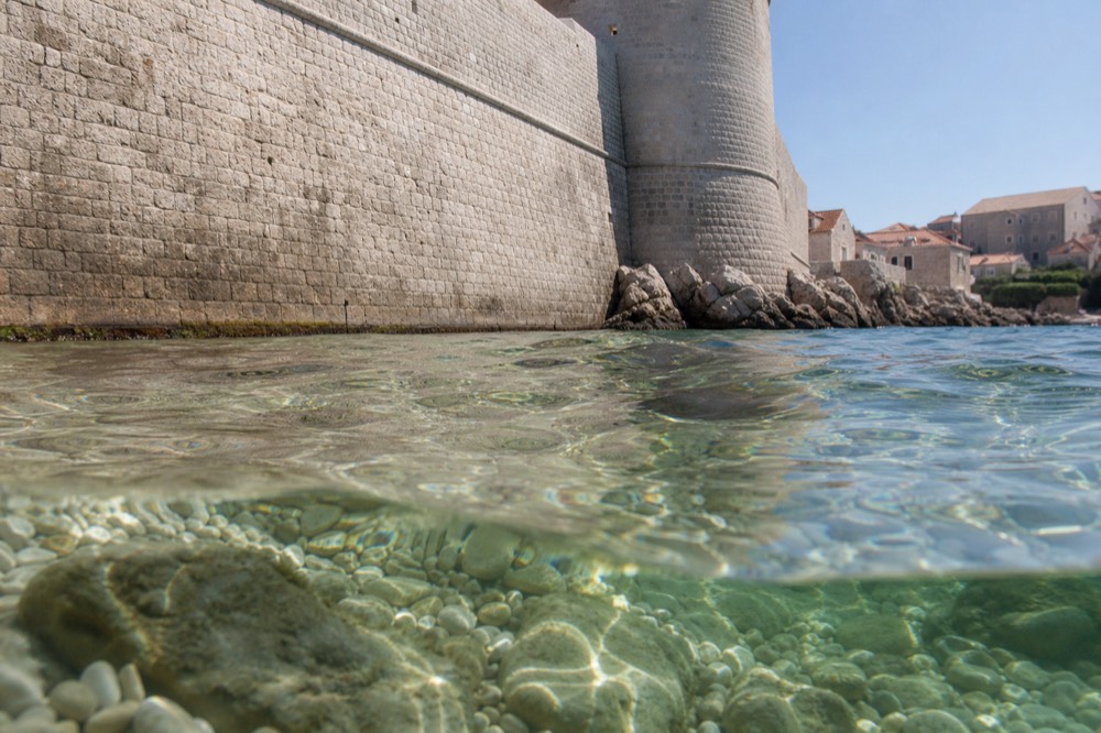 Underwater view of sunlight through very clear water above pale pebbles