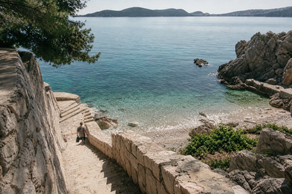 Small pebble cove with clear shallow water and a view of island silhouettes