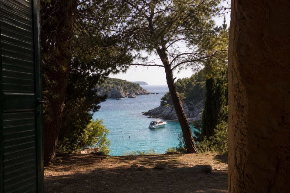 Boat anchored in a turquoise cove with swimmers in the water