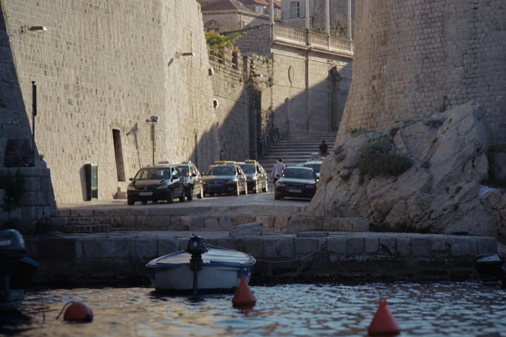 A row of taxis waiting on a rank near the medieval city walls